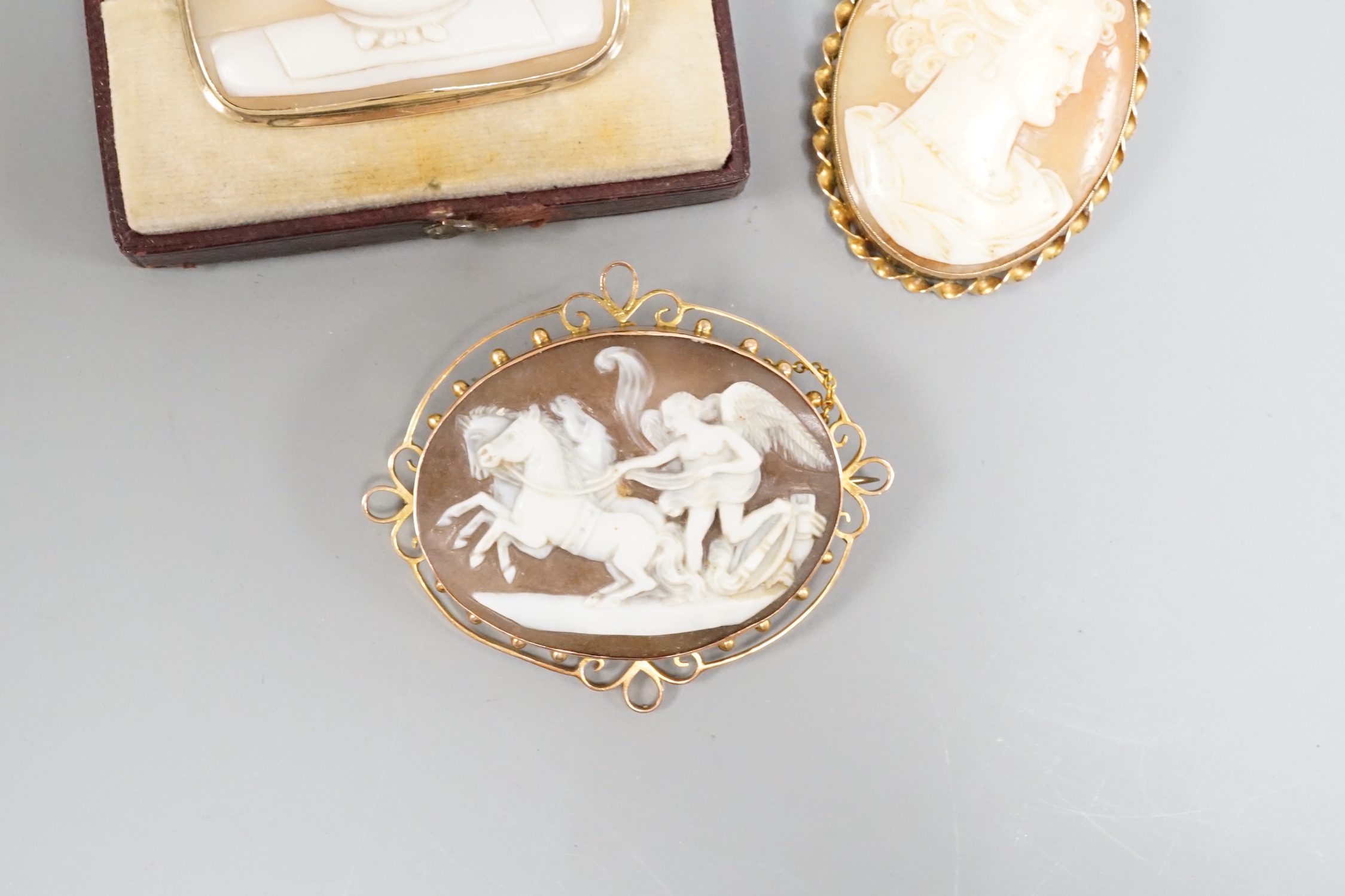An early 20th century 9ct mounted oval cameo shell brooch, 57mm and two other cameo shell brooches including maiden and pliny doves.